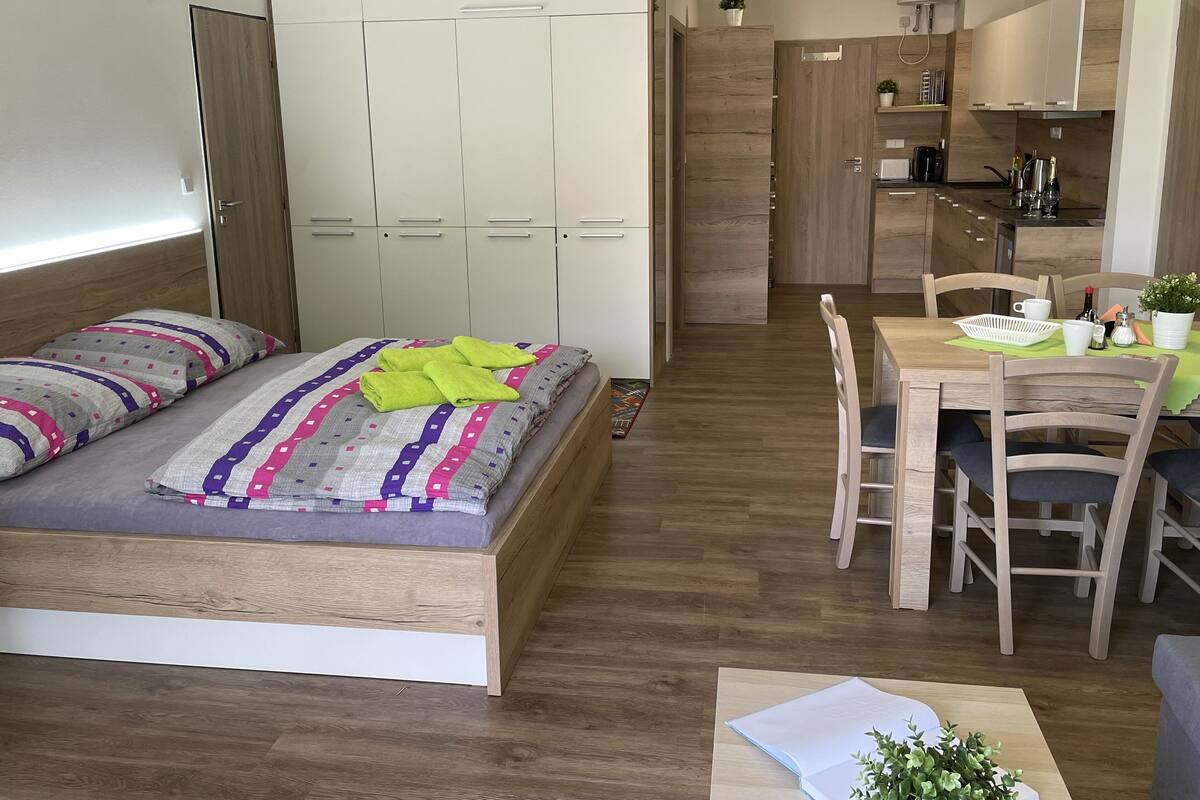 A compact bedroom with a bed, bedside tables, and a small desk with a chair.