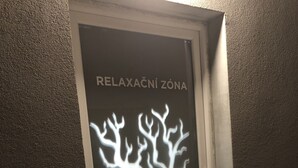 Uma porta com silhueta de árvore e o texto "RELAXAČNÍ ZONA" indicando uma área de relaxamento.