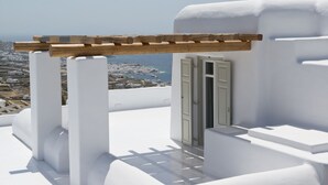 A white building with a wooden pergola and a door. - Villa Opal (Mykonos)