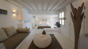 A modern, minimalist bedroom with a large bed, a sofa, and a decorative pouf. - Villa Opal (Mykonos)