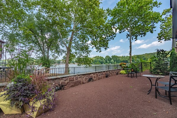 An outdoor patio with stone walls, tables, and chairs overlooking a body of water.