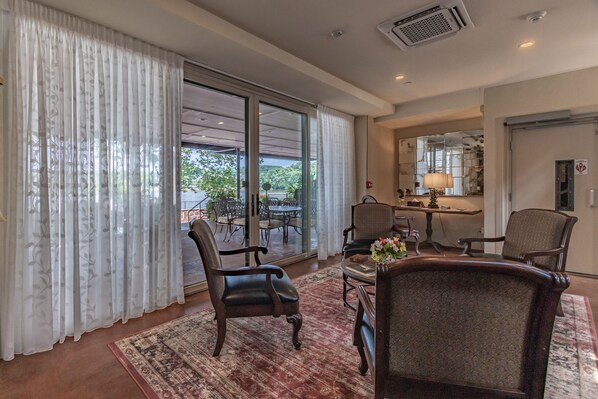 A spacious living room with a large sliding glass door leading to an outdoor patio, a dining area with a table and chairs, and a cozy seating area with a patterned rug. - Carriage House of New Hope (New Hope)