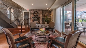 A cozy living area with a stone wall, a fireplace, and a seating arrangement around a coffee table. - Carriage House of New Hope (New Hope)