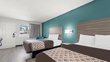 Habitación de hotel con dos camas, un escritorio, una silla, una ventana y una puerta.