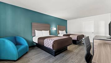 Une chambre d’hôtel avec deux lits, un bureau, une chaise et une porte.