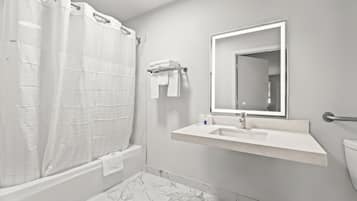 Un baño con ducha, lavabo, inodoro y espejo.