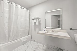 A bathroom with a shower, a sink, a toilet, and a mirror. - Rodeway Inn Cairo (Cairo)