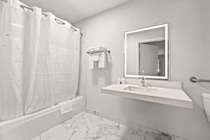 A bathroom with a shower, a sink, a toilet, and a mirror.