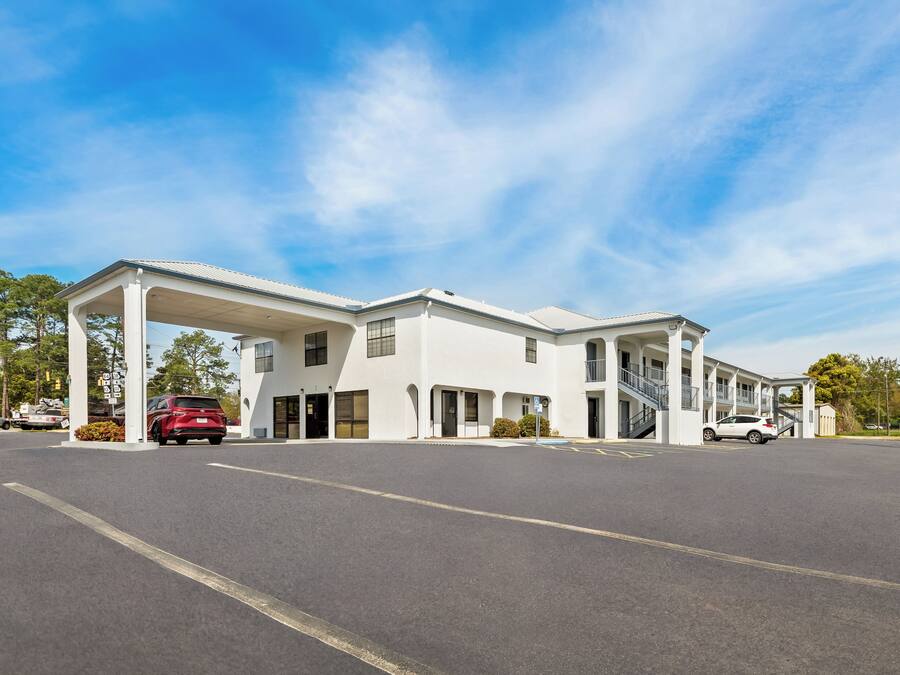 Een meerhoog hotel met een overdekte parkeerplaats en een heldere lucht.