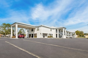 A multi-story hotel with a covered parking area and a clear sky.