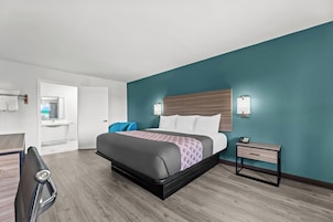 A modern hotel room with a bed, bedside table, and a view of the bathroom.