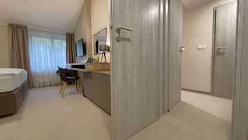 A hotel room with a bed, a desk with a chair, a TV, and a wardrobe.