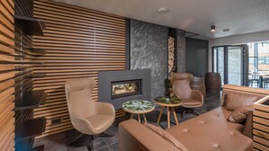 Een modern interieur met een open haard, lederen zitmeubels en een accentmuur van steen.