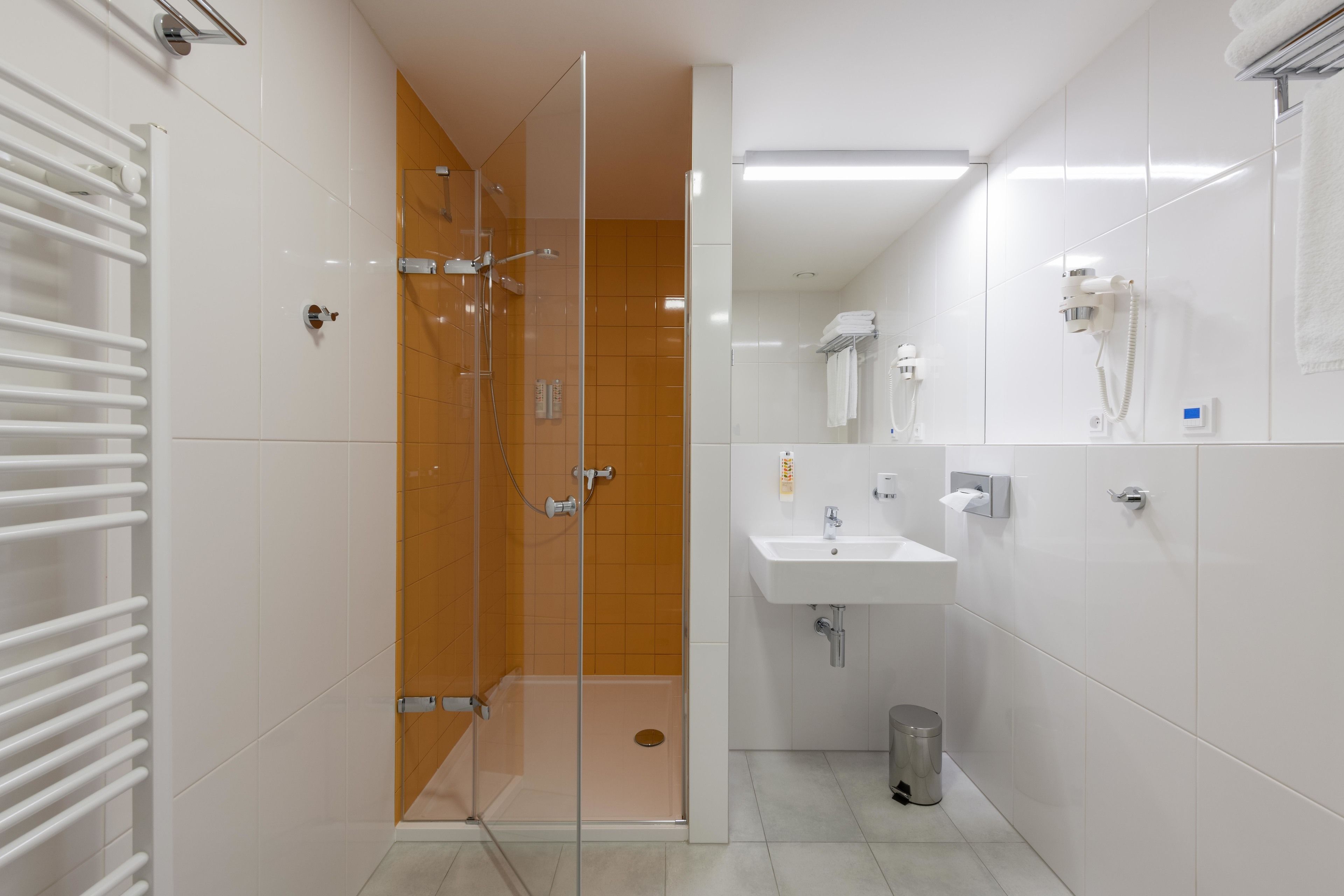 A modern bathroom with a glass-enclosed shower, a white sink, and a towel rack.
