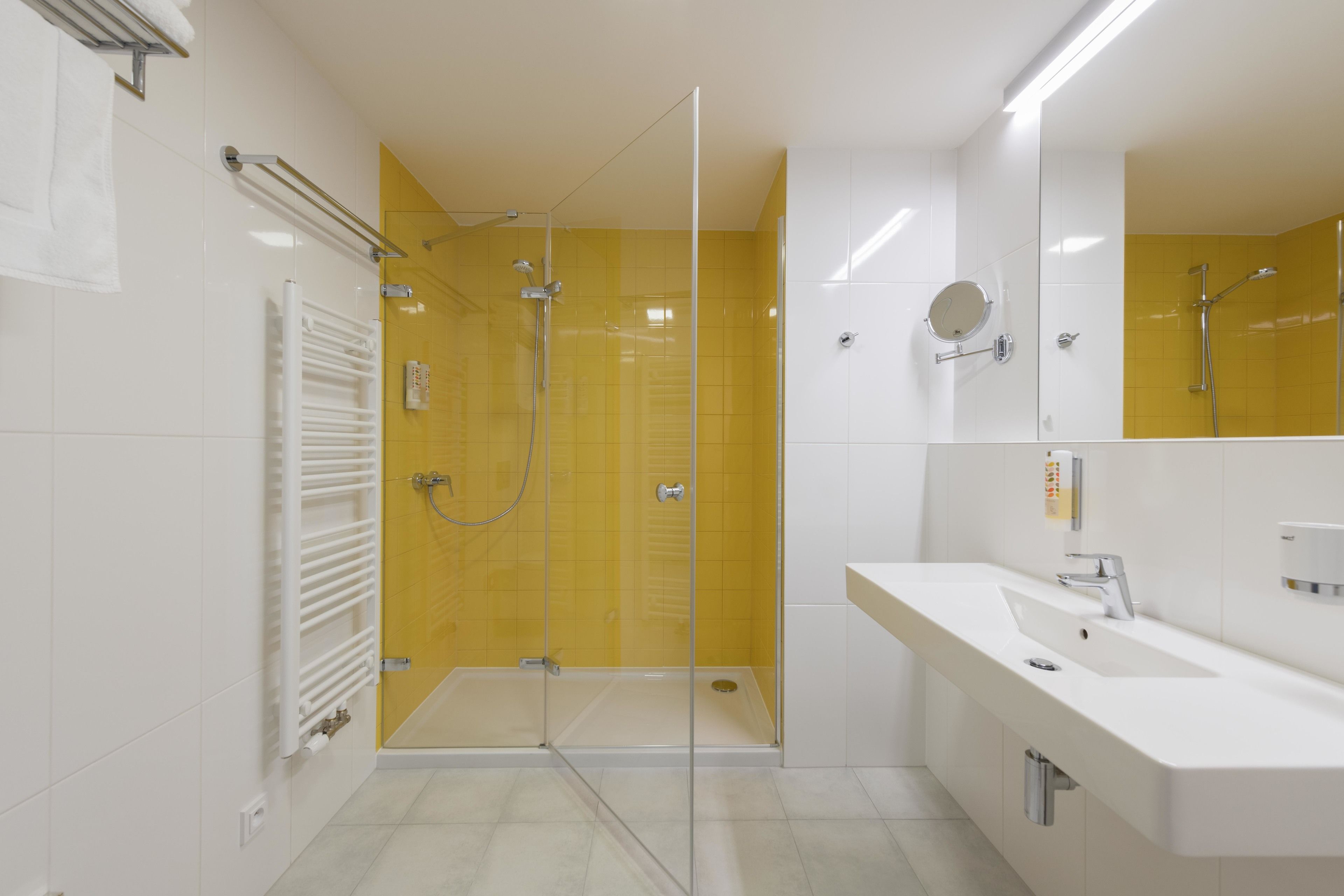 Une salle de bain moderne avec une douche à parois de verre, un lavabo blanc et un miroir au-dessus.