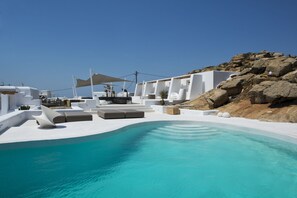 A modern pool area with white architecture and a clear blue pool. - Amethyst Suite (Mykonos)