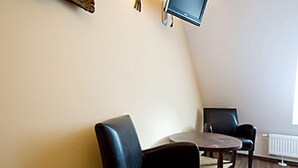 A room with a wooden ceiling, a framed painting, a flat-screen TV, and two chairs. - Kleine Villa Rose (Eltville am Rhein)