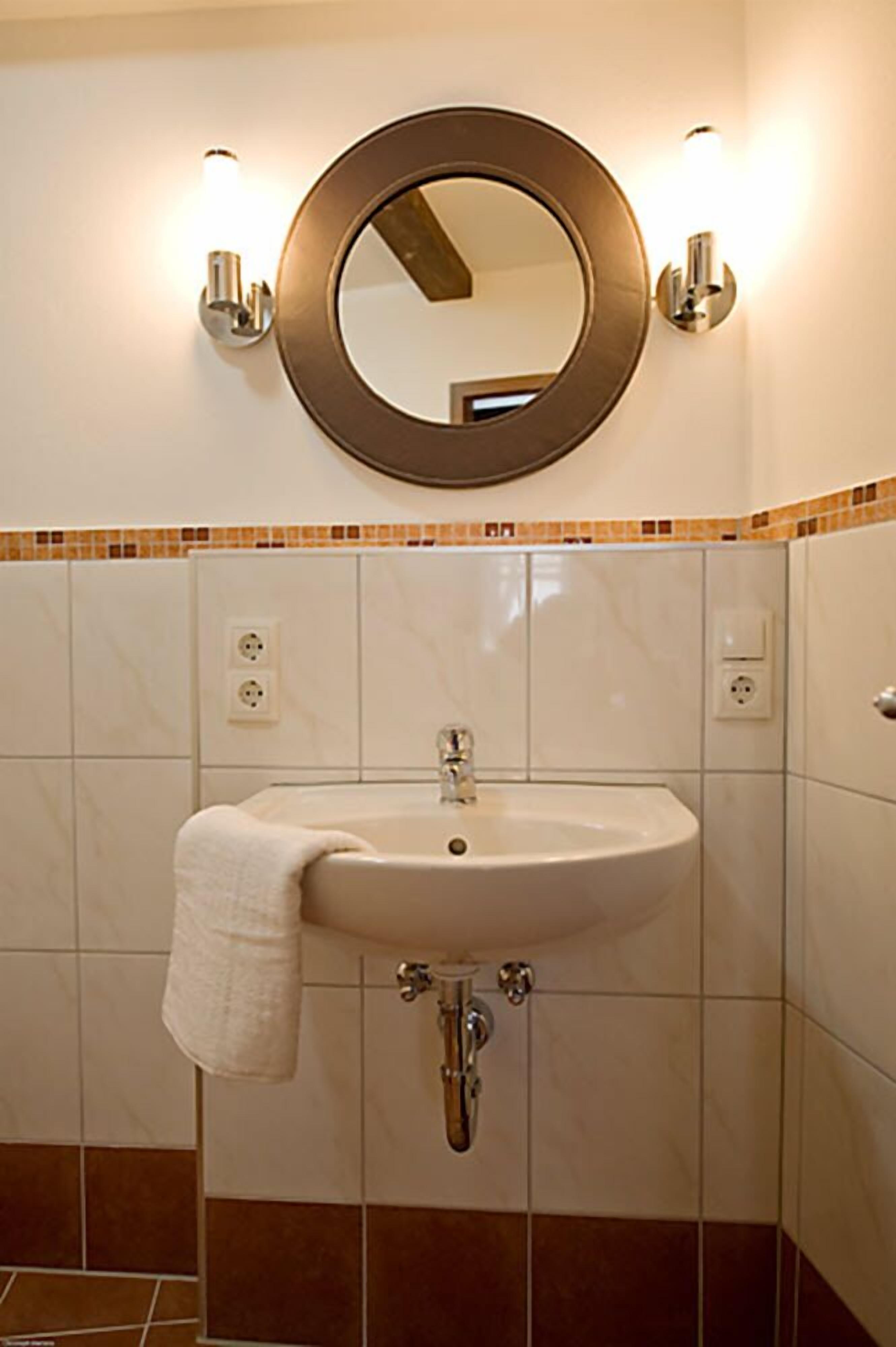 Une salle de bain avec un miroir rond, un lavabo et une serviette accrochée au mur.