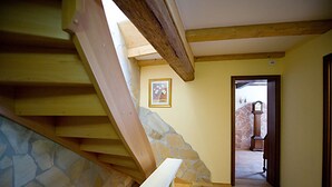 A wooden staircase with stone accents leading to a room with a door and a stone wall. - Kleine Villa Rose (Eltville am Rhein)