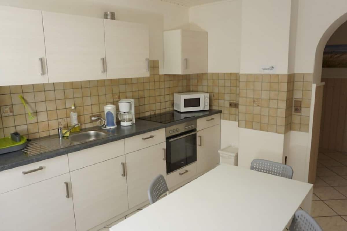 A small kitchen with white cabinets, a microwave, a coffee maker, and a sink.