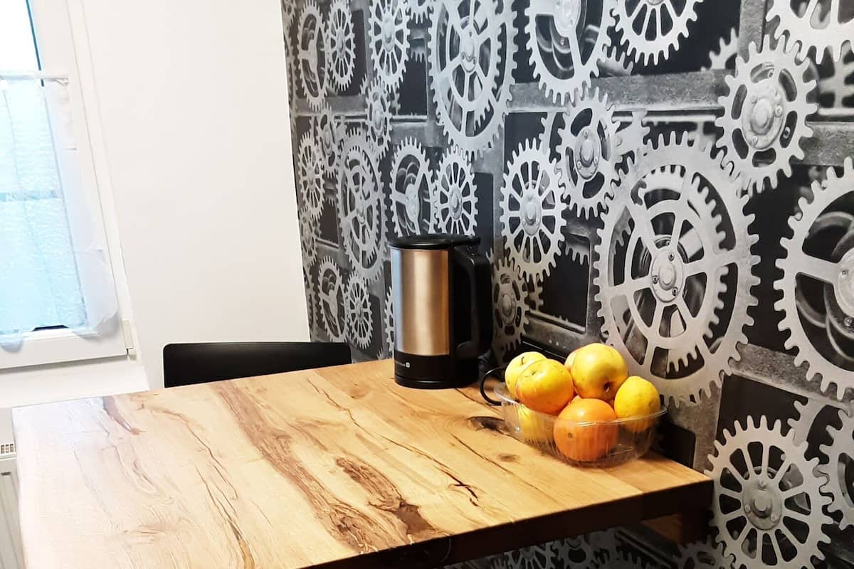 A wooden table with a black coffee pot and a bowl of lemons and oranges.