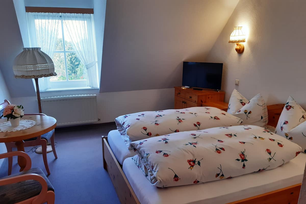 A bedroom with a bed, a TV, a desk, and a lamp.