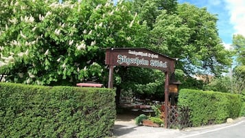 Une enseigne pour un hôtel appelé « Jägermeister Schloss », doté d’un jardin bien entretenu et d’une entrée dallée.