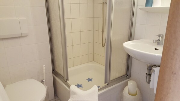 A bathroom with a shower, toilet, and sink.