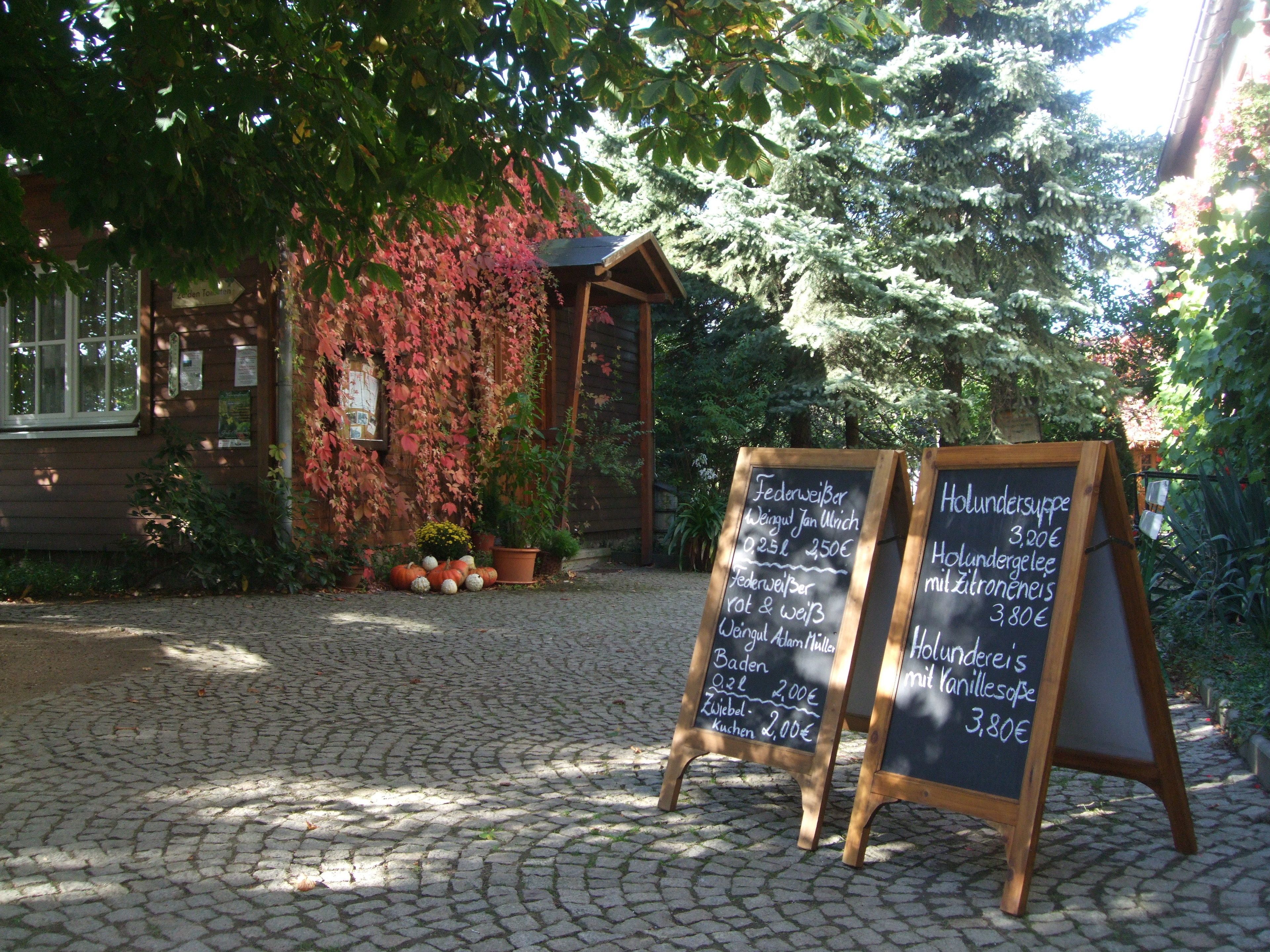 A rustic wooden building with a signboard displaying menu items and prices.