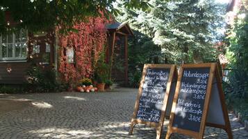 A rustic wooden building with a signboard displaying menu items and prices.