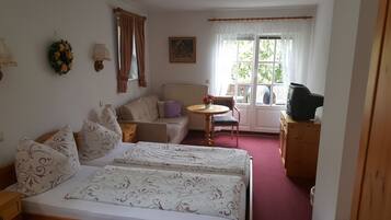 Une chambre avec deux lits, un canapé, une petite table, un téléviseur et une fenêtre avec des rideaux.