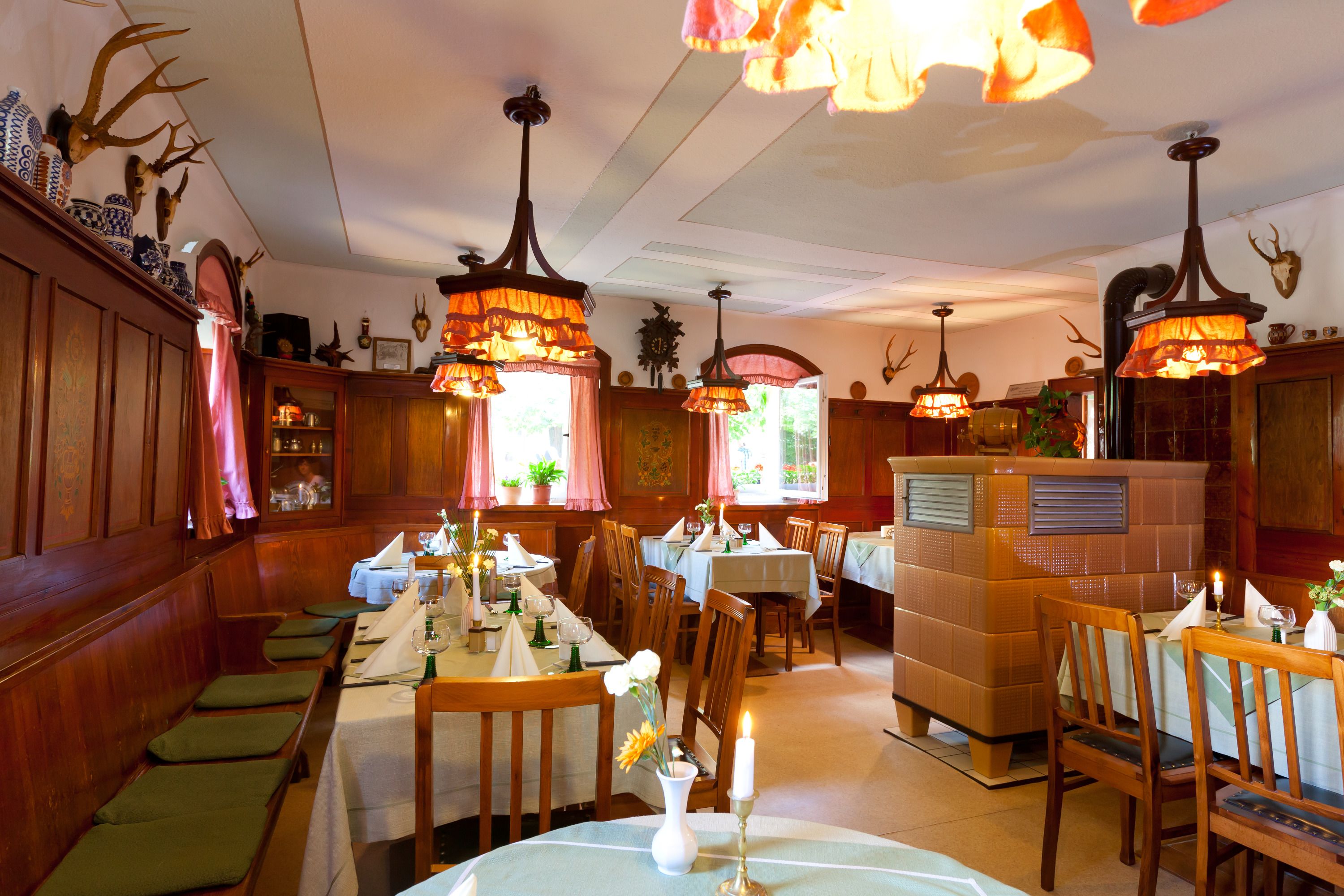 A restaurant with wooden booths, tables set for dining, and decorative antlers on the walls.