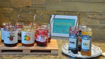 Verschiedene Gläser Marmelade mit Löffeln, auf einer Holzbrett und einer dekorativen Tablett angeordnet.