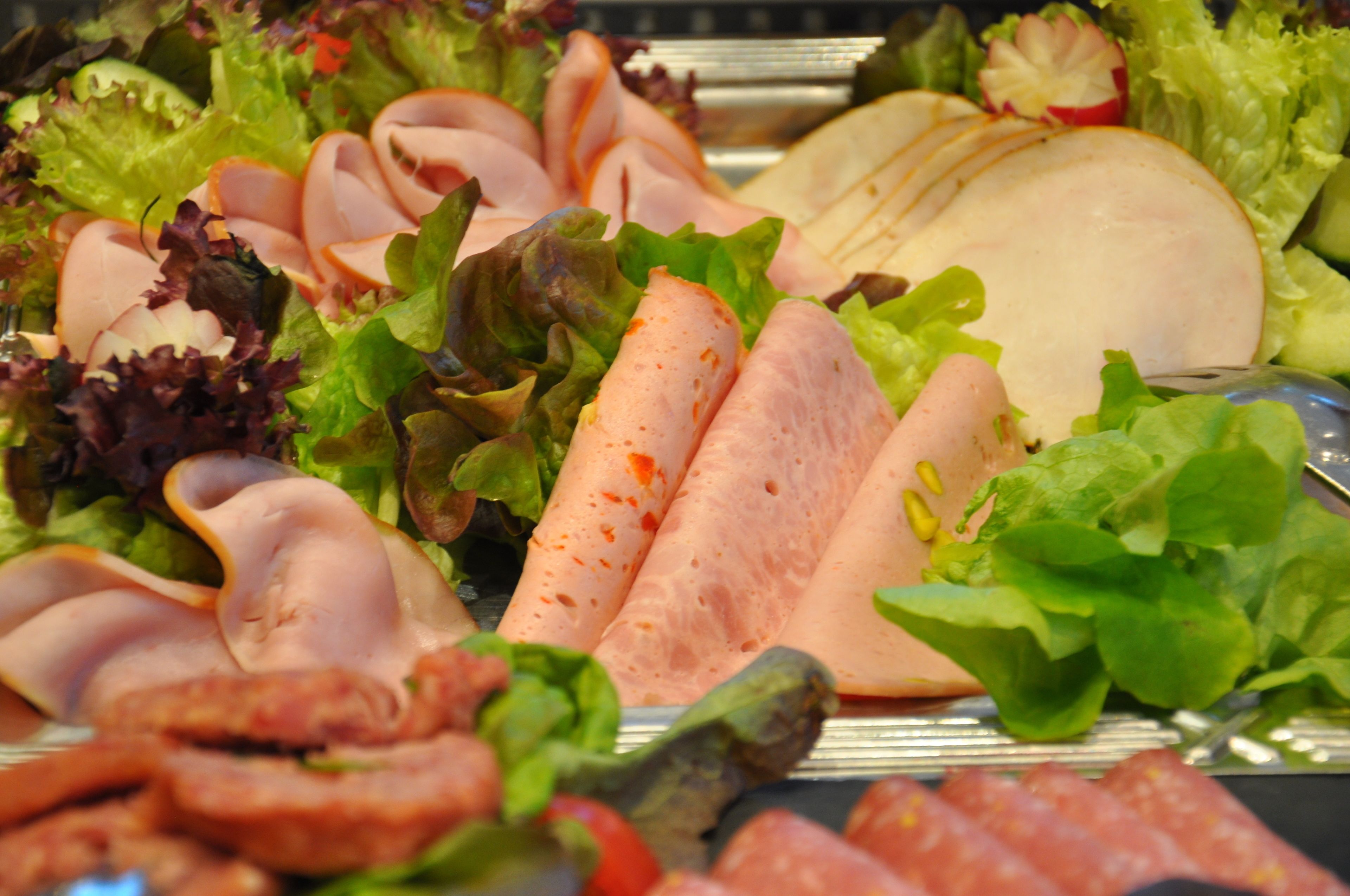 A variety of sliced meats and fresh vegetables on a platter.
