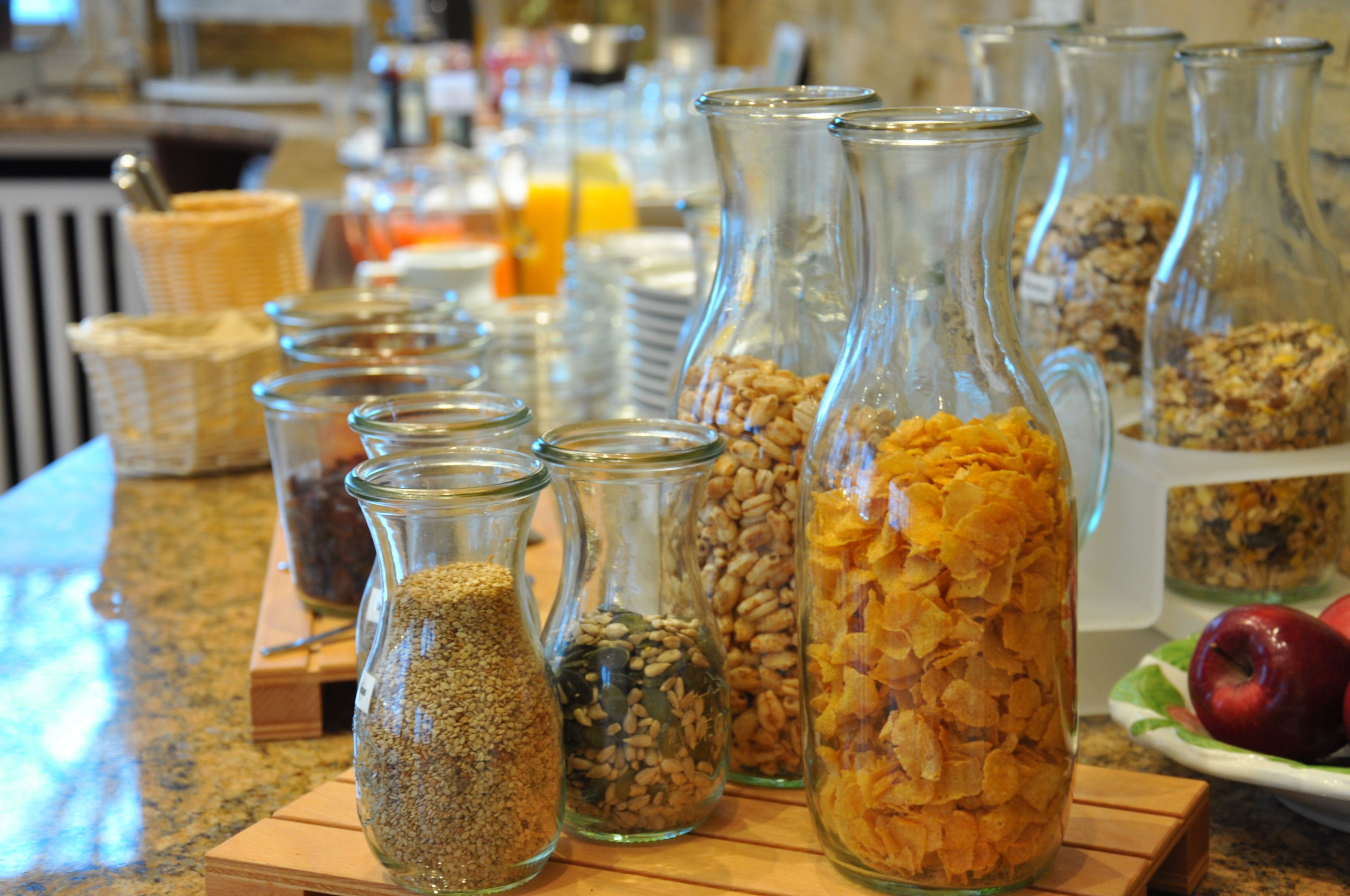 Buffet de café da manhã com diversos alimentos em recipientes de vidro.