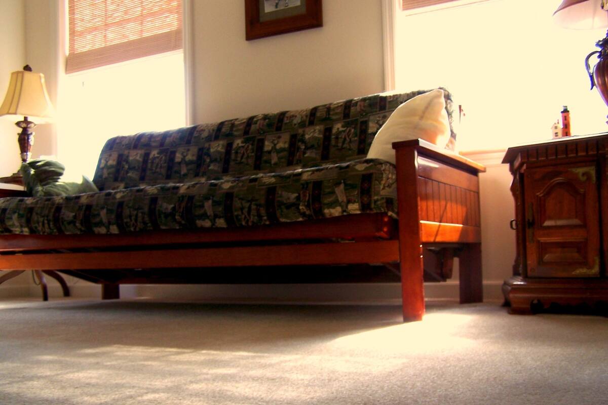 Une chambre à coucher avec un lit, une table de chevet, une lampe et une fenêtre avec des stores.