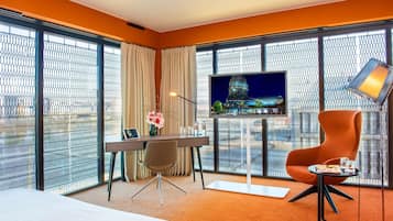 Una habitación de hotel con una cama, un escritorio con computadora, televisor y una silla.