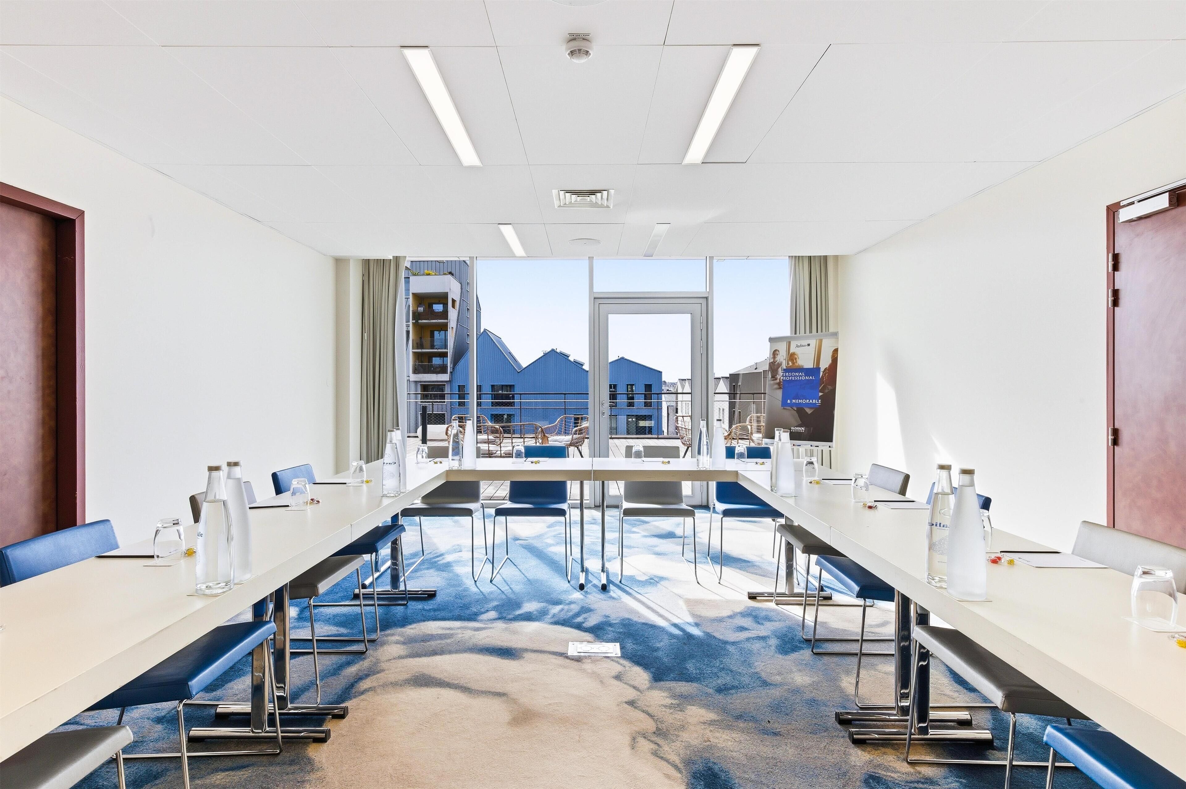 A conference room with a long table, chairs, and a view of mountains through large windows.