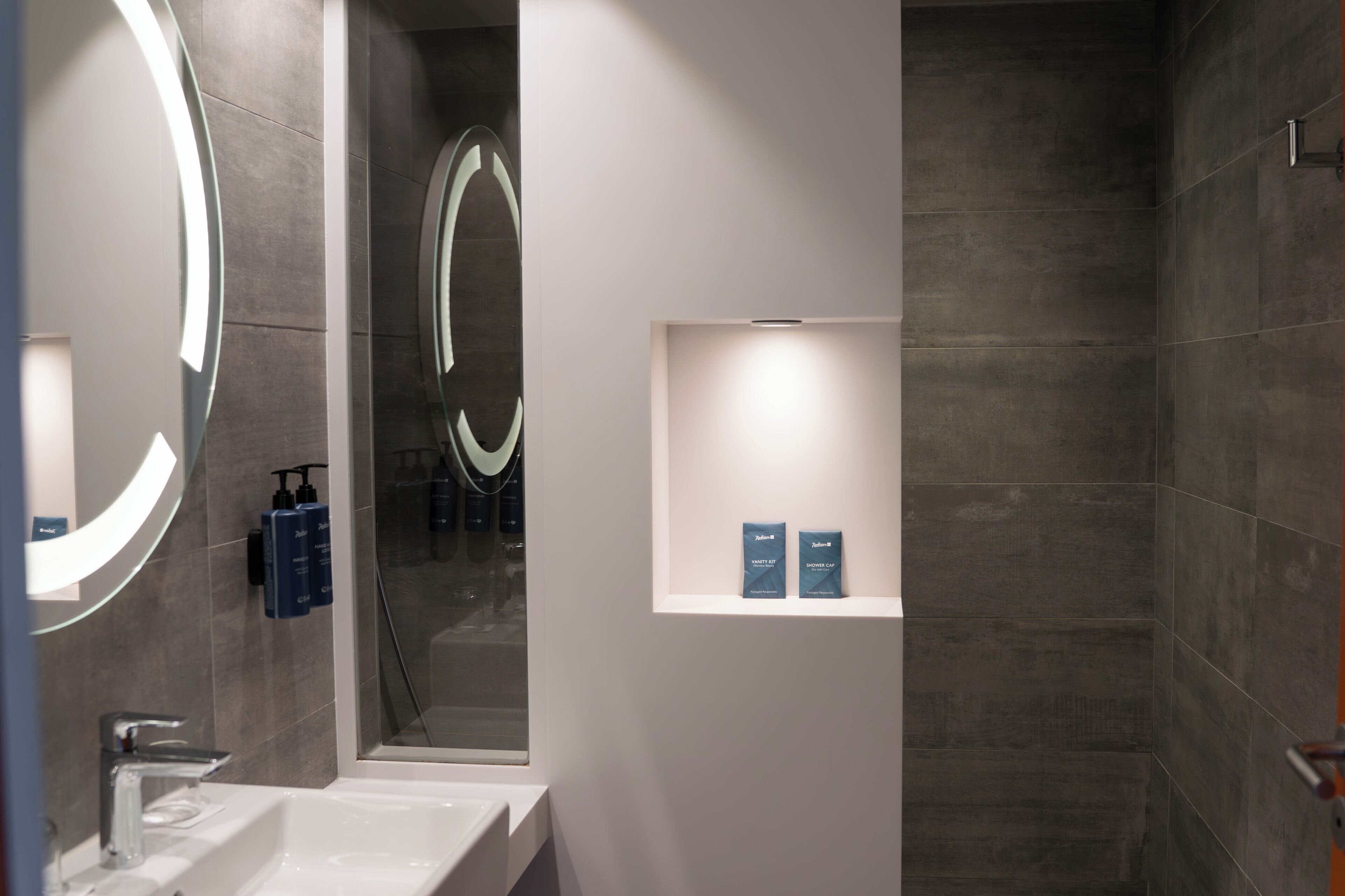 Un baño moderno con un espejo grande, un lavabo y una zona de ducha.