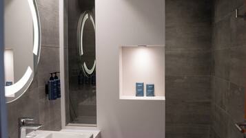 Un baño moderno con un espejo grande, un lavabo y una zona de ducha.
