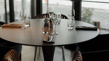 Una mesa redonda para comer con copas de vino, una botella y un menú. La mesa está dispuesta para cuatro personas.