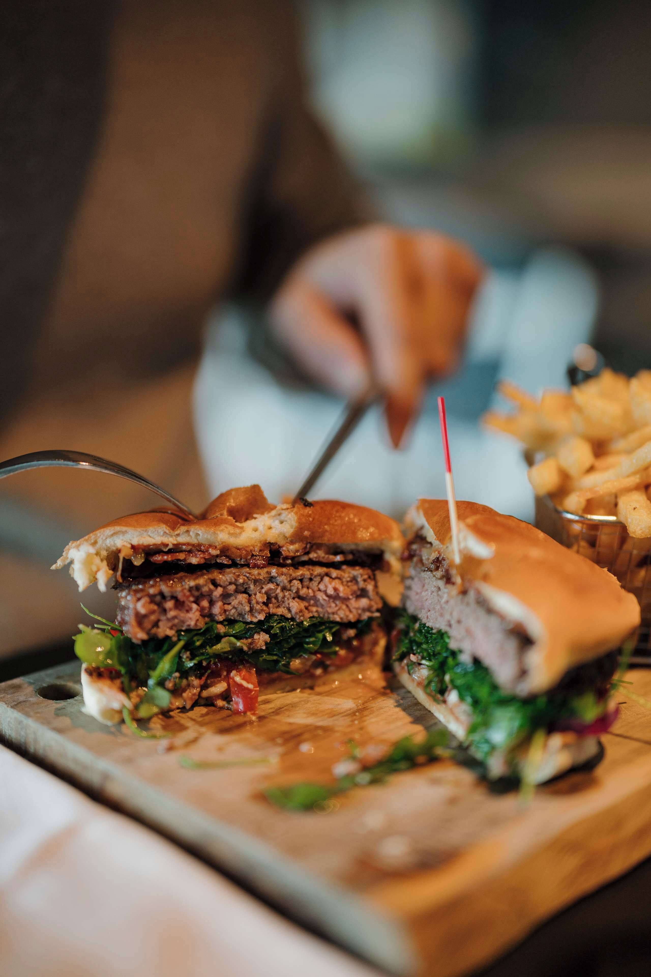 A sandwich cut in half with a toothpick, placed on a wooden board.