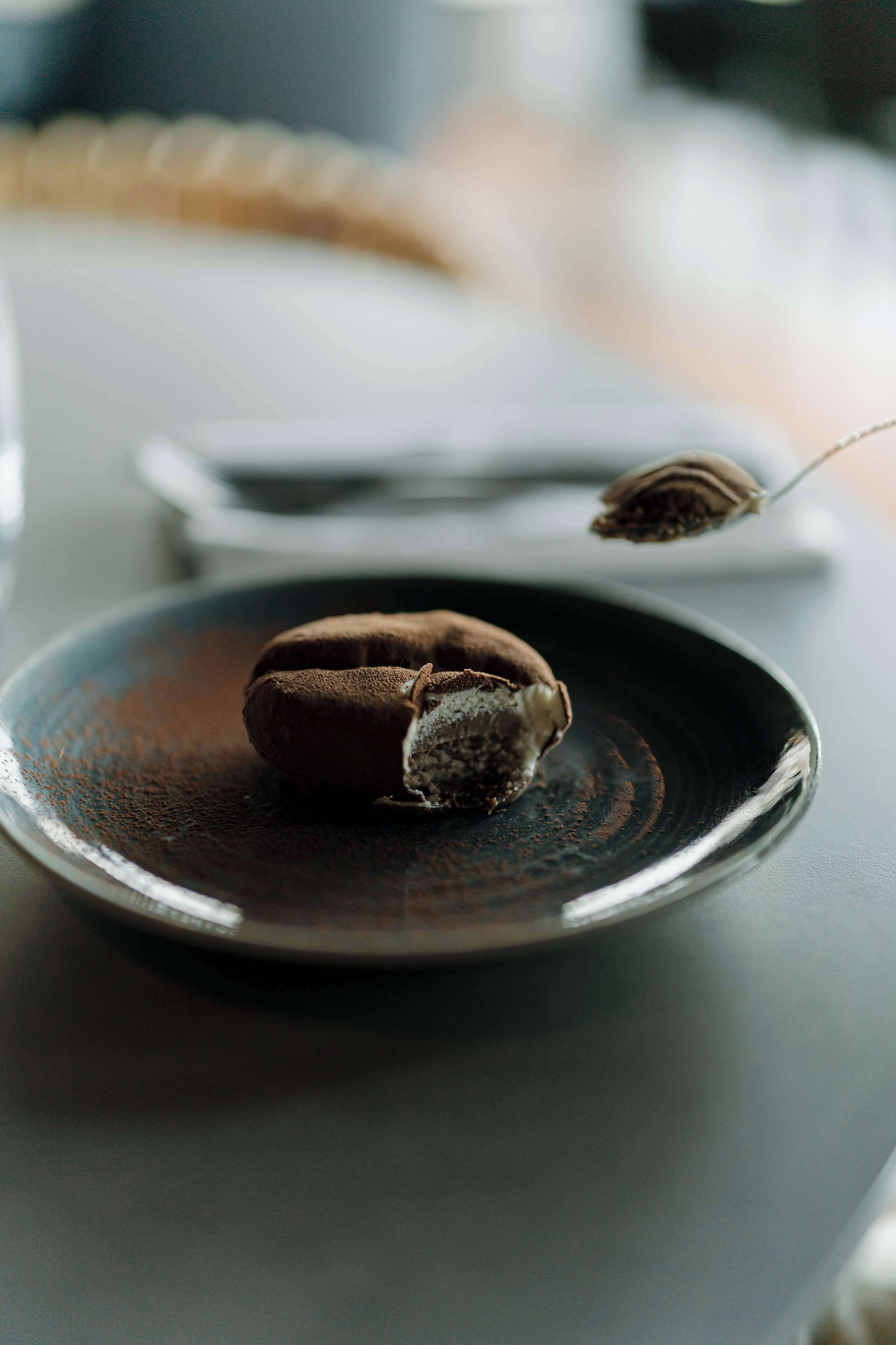 A dessert on a plate with a spoonful of powder beside it.