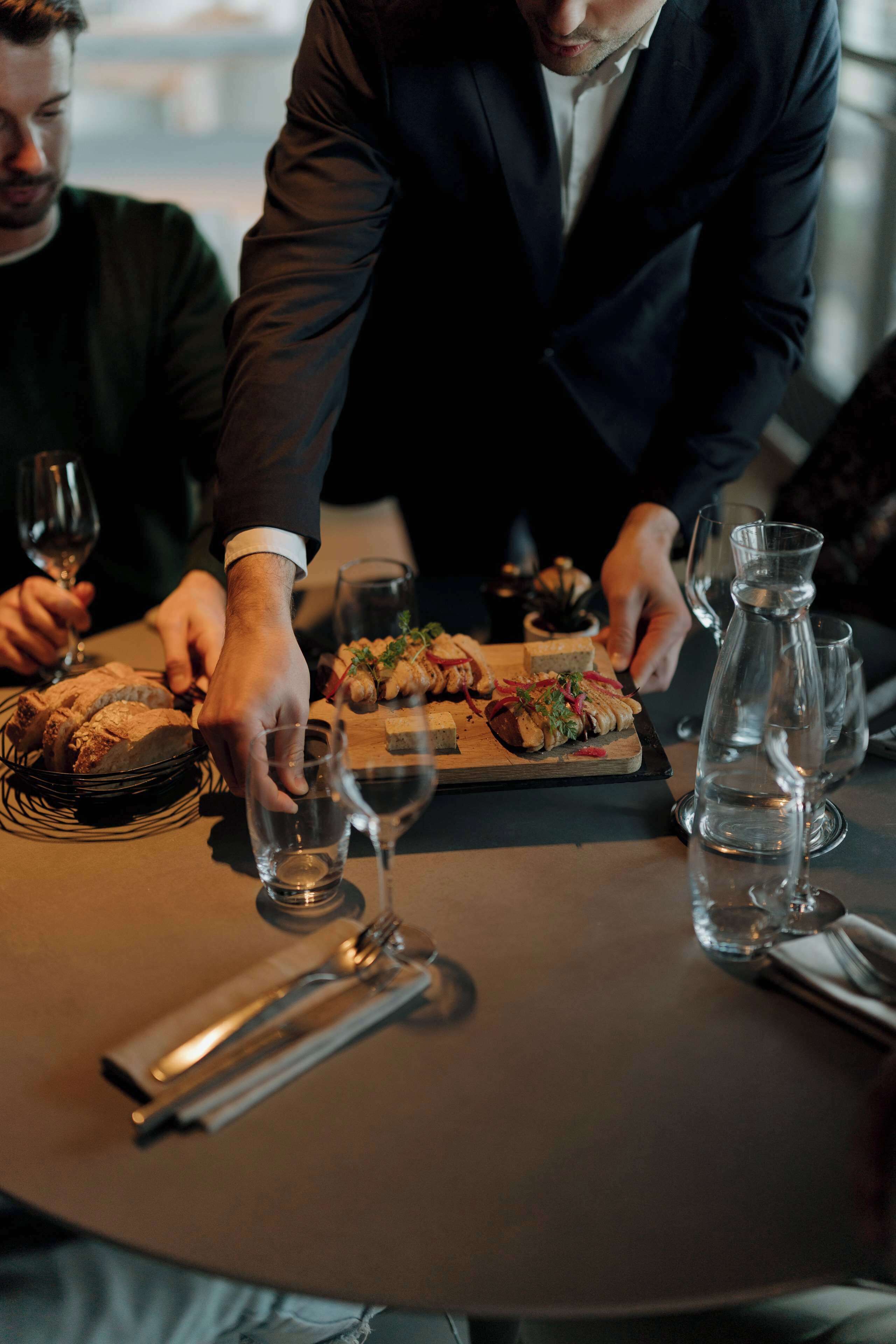Una mesa de comedor con comida, copas de vino y una jarra de agua.