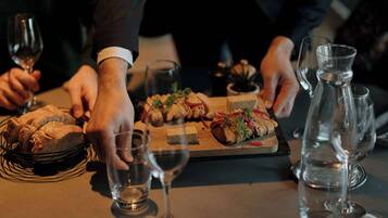 Una mesa de comedor con comida, copas de vino y una jarra de agua.