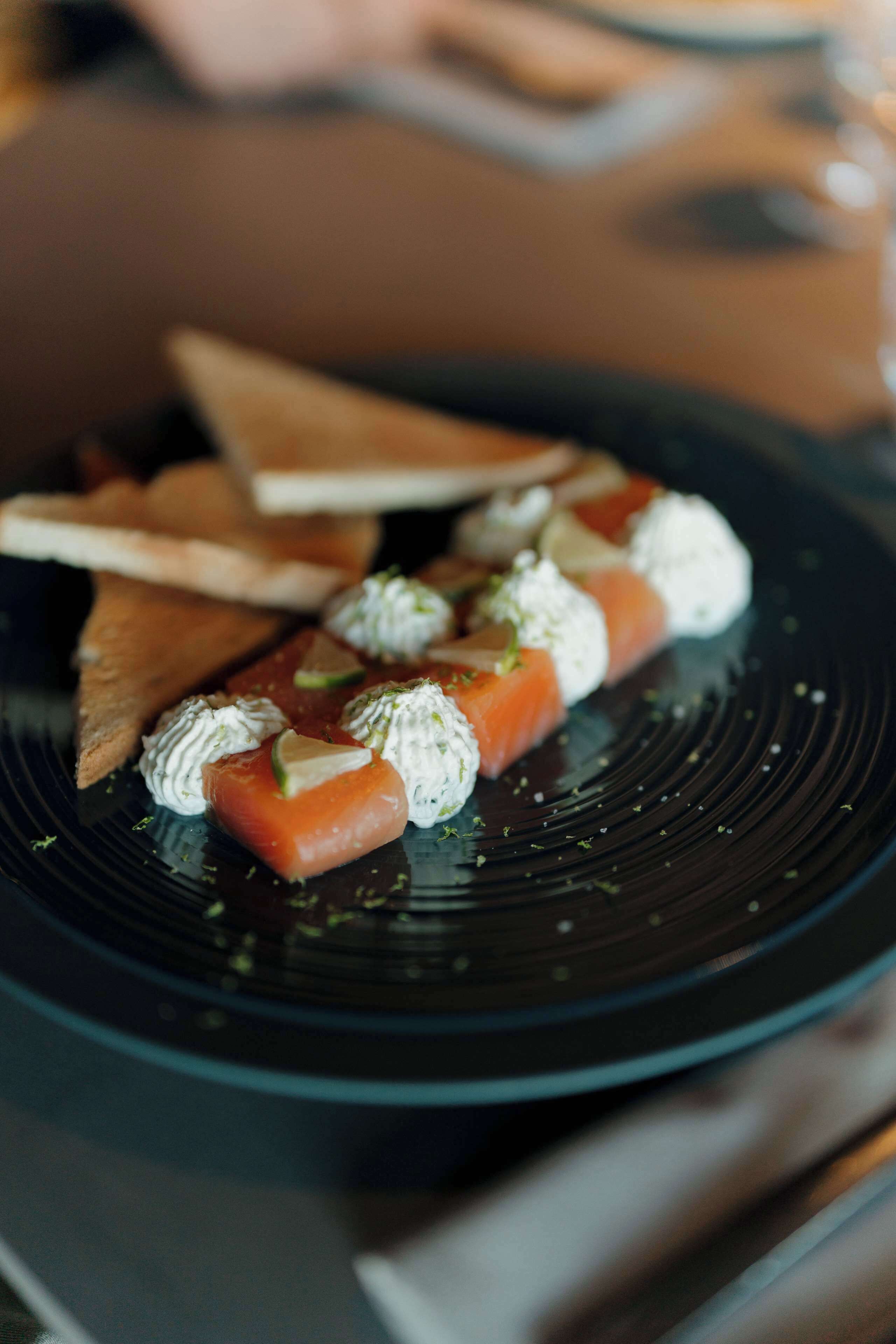 Un plato de sushi con un plato negro y una tabla de madera al fondo.