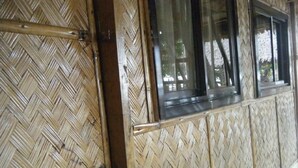 A room with a woven bamboo wall and a window with a metal frame. - Paniman Bay lodge (Caramoan)