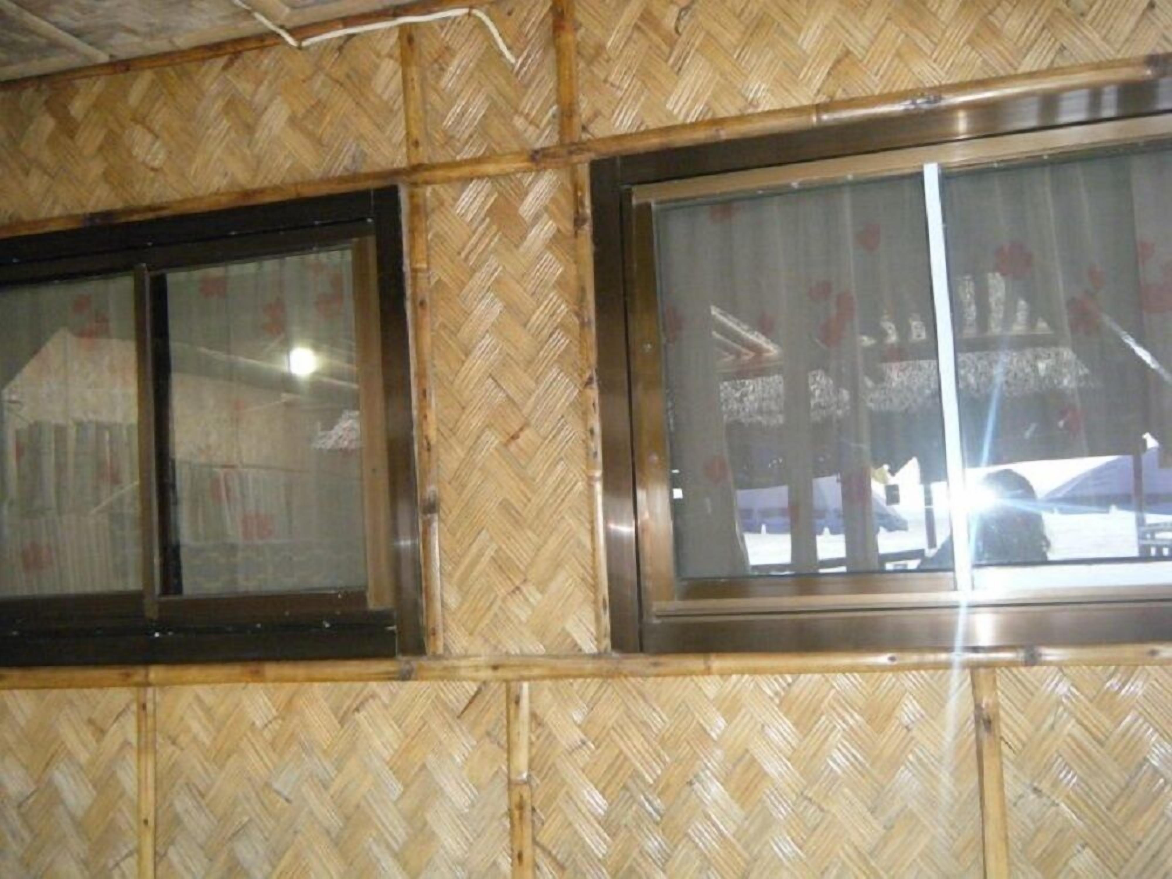 A room with a herringbone-patterned wall and two windows with metal frames.