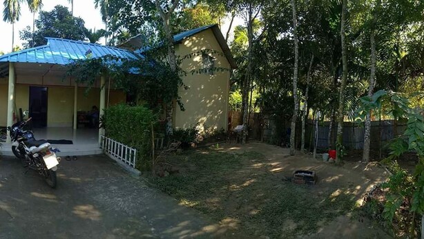 A single-story building with a blue roof, a covered porch, and a motorcycle parked in front. - Nilborno Cottage (Kamalganj)