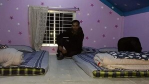 A room with two beds, a window with curtains, and star-patterned walls. - Nilborno Cottage (Kamalganj)